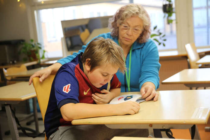 Koulumummi Helena Kinnunen kuuntelee, kun toisluokkalainen Miko lukee hänelle ääneen kirjaa. Aikuinen auttaa tarvittaessa ja yhdessä voidaan pohtia tarinan sisältöä.